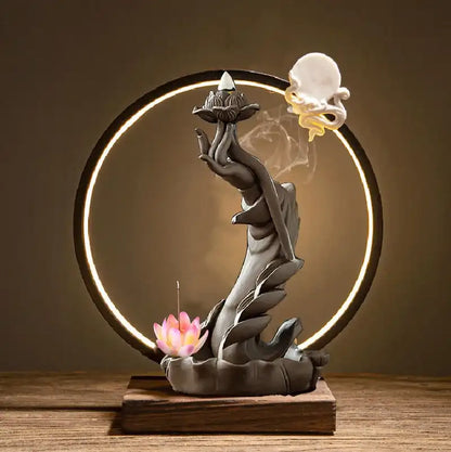 Decorative incense burner with hands holding lotus flowers on a wooden base.