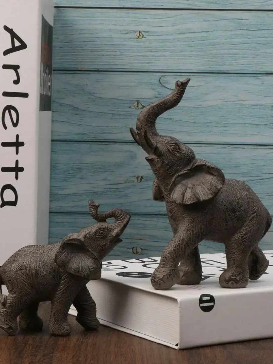 Two elephant figurines on a box with a wooden background