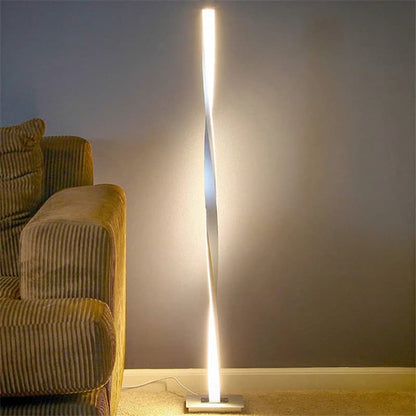 Modern floor lamp casting light on a wall next to a textured sofa.