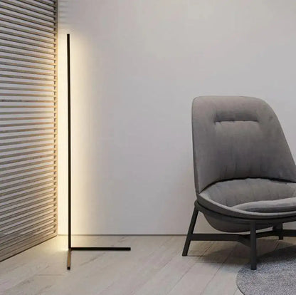 Modern gray chair next to a tall floor lamp in a minimalistic room.
