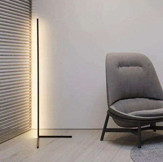 Modern gray chair next to a tall floor lamp in a minimalistic room.