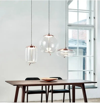 Modern dining room with glass pendant lights hanging above a wooden table.