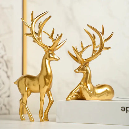 Two gold deer figurines on a white surface with a light background