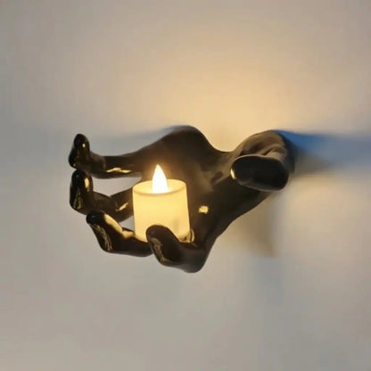 Decorative wall sconce shaped like a half hand holding a candle against a plain background