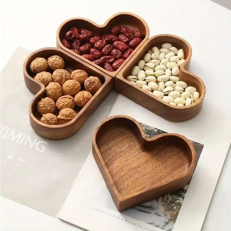 Wooden heart-shaped compartmentalized dish with nuts and dried fruits on a magazine