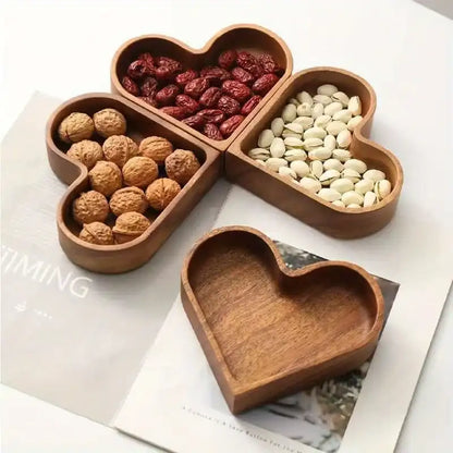 Wooden heart-shaped compartmentalized dish with nuts and dried fruits on a magazine