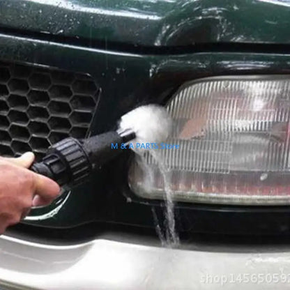 Person washing a car with a high-pressure water gun, focusing on the front grille and headlight.