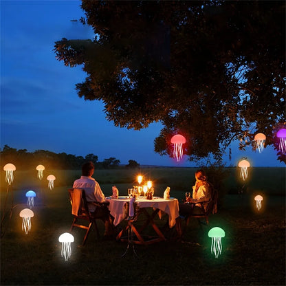 Two people sitting at a table under jellyfish-shaped lights in a dark outdoor setting.