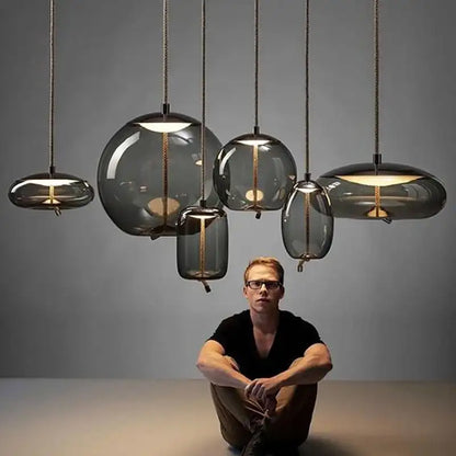 Man sitting on the floor with modern pendant lights hanging above him against a gray background
