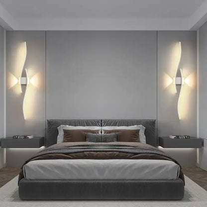 Modern bedroom with a bed, nightstands, and wall lights.