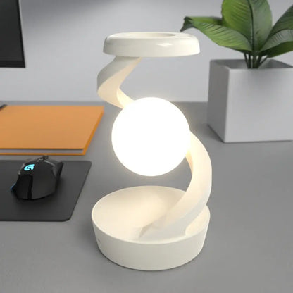 Modern white desk lamp on a gray surface with a plant and office items in the background