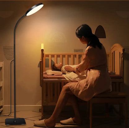 Woman tending to a child in a crib with a standing lamp illuminating the room.