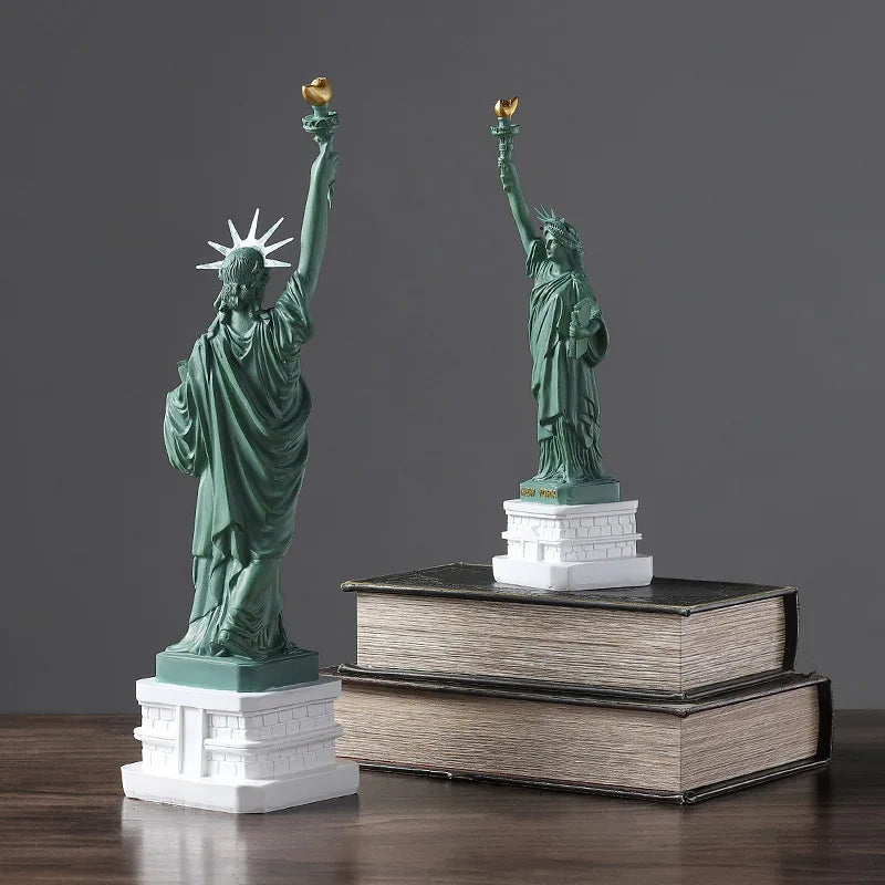 Two miniature statues of Liberty on books against a gray background