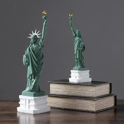 Two miniature statues of Liberty on books against a gray background