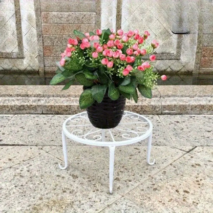 Potted plant with pink flowers on a decorative metal stand in front of stone steps.