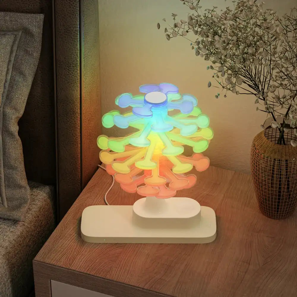 Colorful tree-shaped lamp on a wooden nightstand with a plant in the background