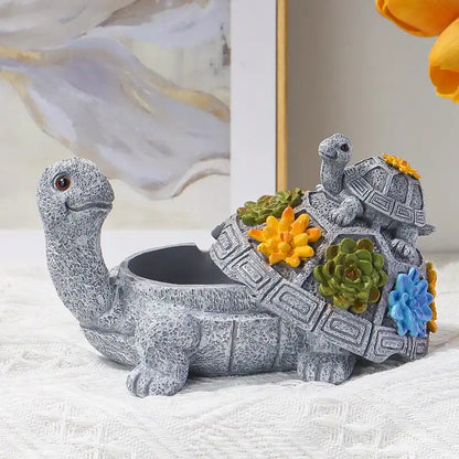 Decorative turtle figurine with succulents on a textured surface