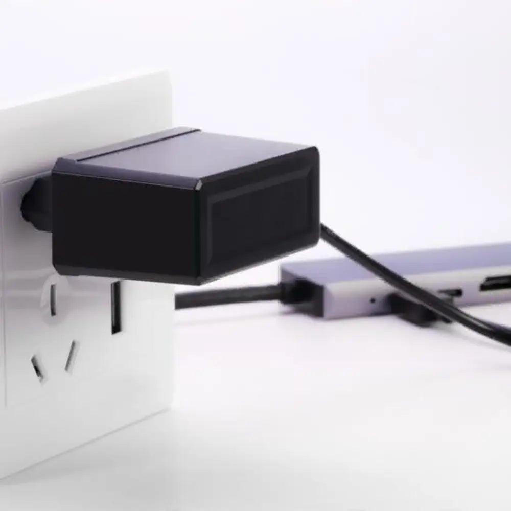 Black power adapter plugged into a wall socket with a white background