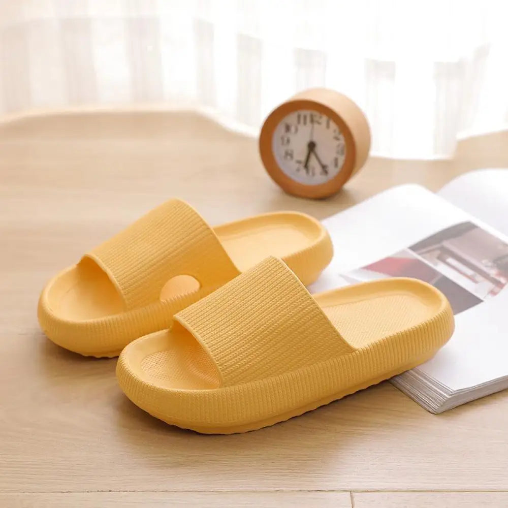 Yellow slippers on a wooden surface with a clock and magazine in the background