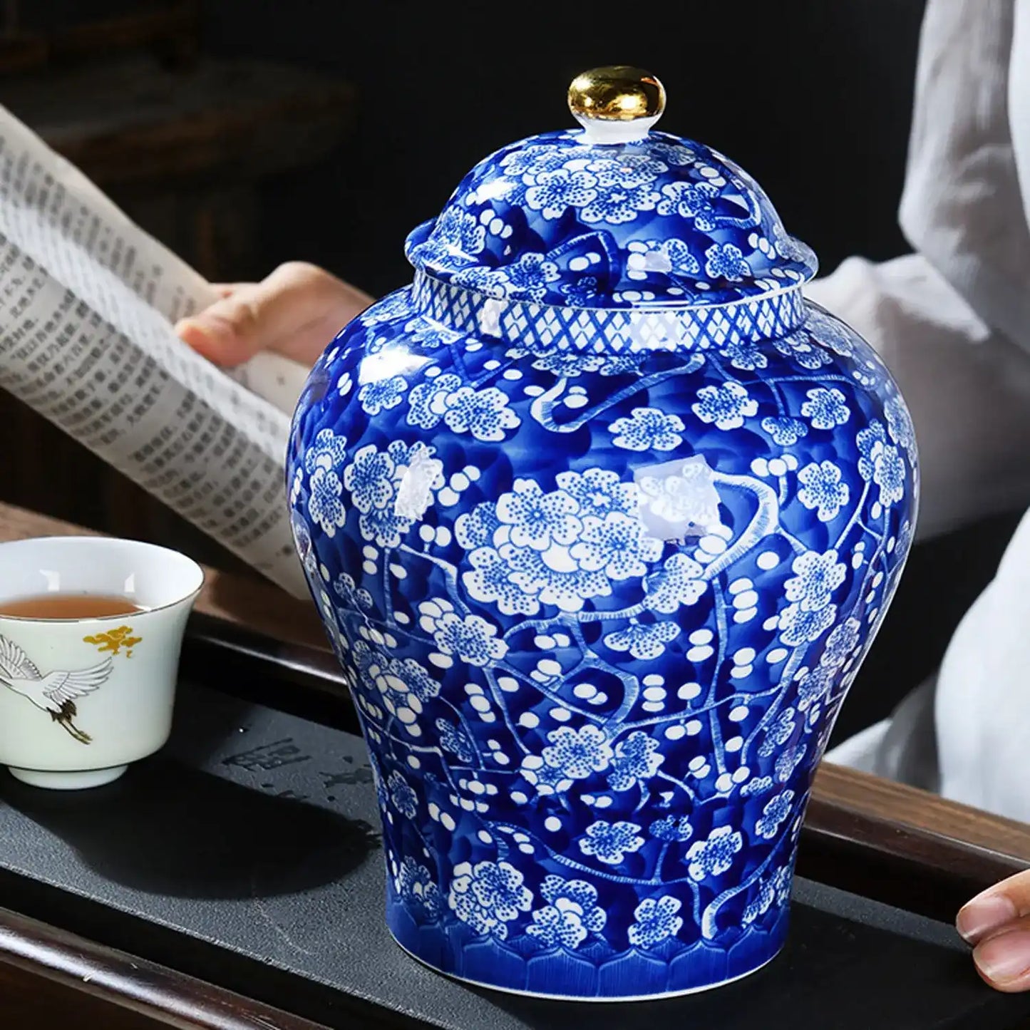 Blue and white ceramic jar with floral patterns on a table.
