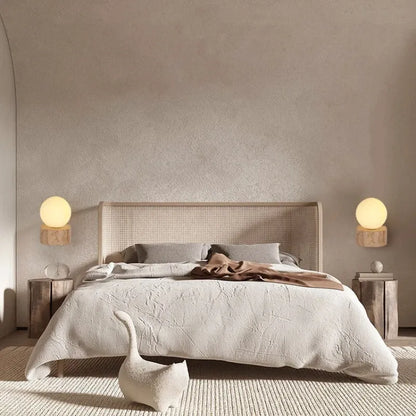 Neatly made bed with beige bedding in a room with neutral walls and lamps.