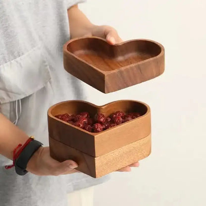 Person holding a wooden heart-shaped box with a smaller heart-shaped dish on top.
